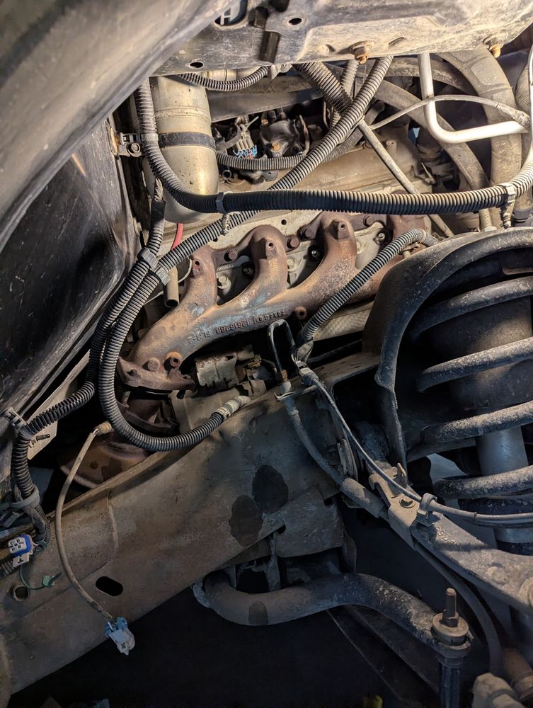 Before: old rusty passenger-side exhaust manifold on a 2013 GMC Sierra